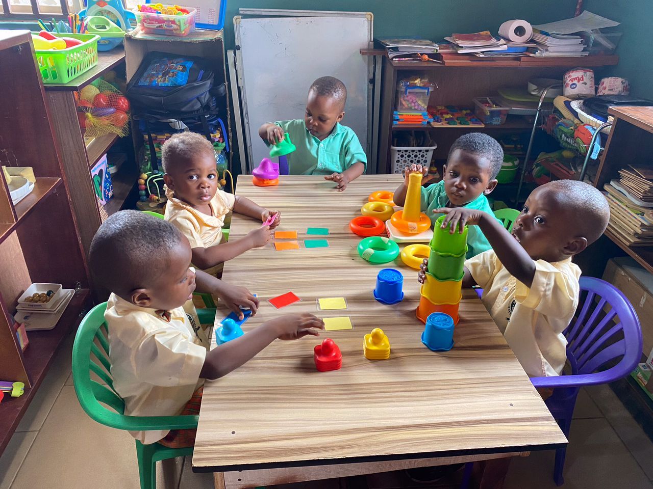 Young pupils at a table doing practical-life work with stacking rings, coloured cups and colour cards